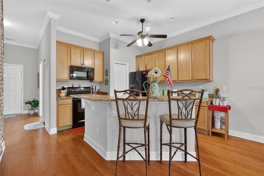 A kitchen with a granite-topped island, wooden cabinets, and a large wall art display — 1010 GREEN GATE BOULEVARD, GROVELAND, FL