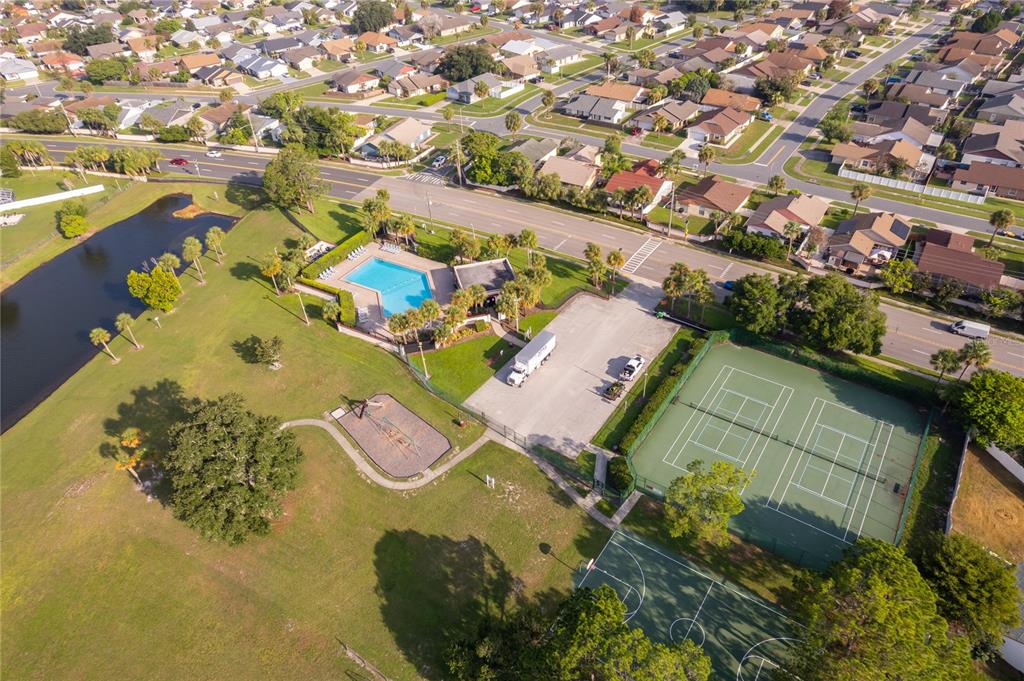 An aerial view shows a community park with a swimming pool, tennis courts, and playground — 4779 WARRIOR LANE, KISSIMMEE, FL