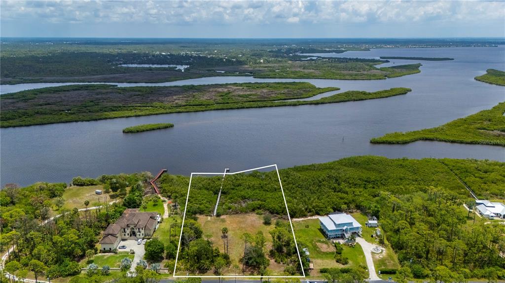 An aerial view shows a vacant waterfront lot outlined in white between two houses — 0 RIVERFRONT DRIVE Lot 6, VENICE, FL