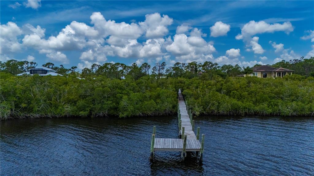 A wooden dock extends from a shoreline covered in dense green mangroves toward open water — 0 RIVERFRONT DRIVE Lot 6, VENICE, FL