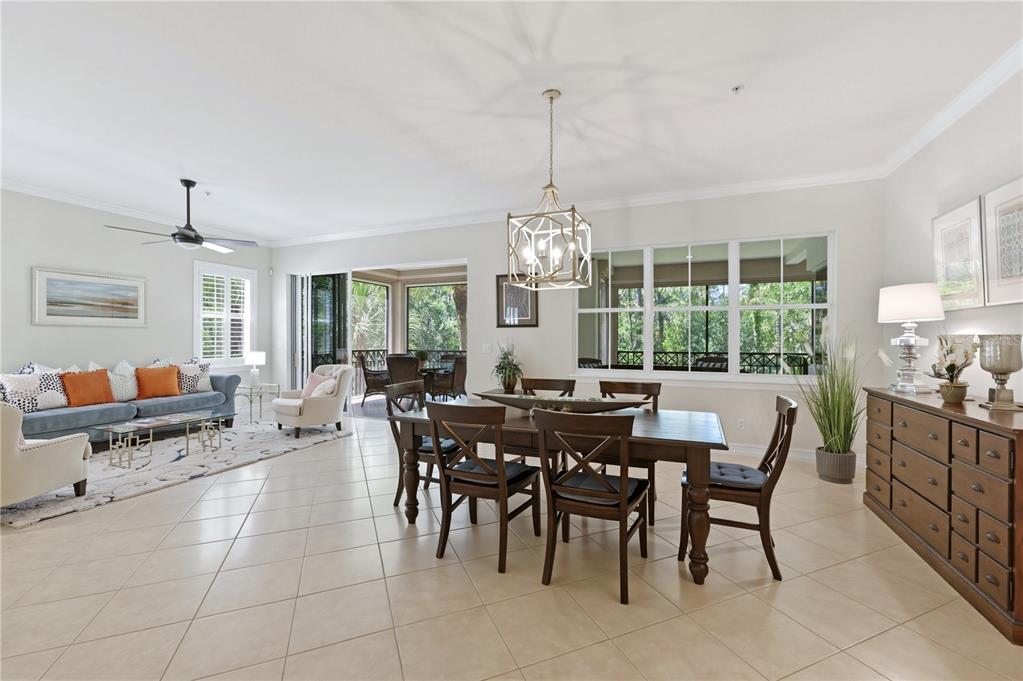 A bright, open-concept living and dining area features tile flooring, a chandelier, and a lanai — 2859 TIBURON BOULEVARD E UNIT 102, NAPLES, FL