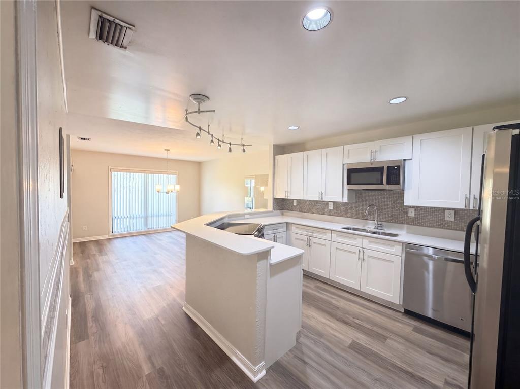 A kitchen with white cabinets and stainless steel appliances opens to a dining area — 109 TUXFORD DRIVE, HAINES CITY, FL