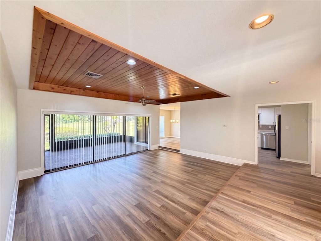 A living room features wood-plank ceiling detail, wood-look flooring, and a large sliding glass door — 109 TUXFORD DRIVE, HAINES CITY, FL