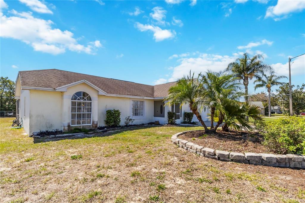 A single-story house with a beige stucco exterior, a brown shingled roof, and a palm tree — 959 LOMA BONITA DRIVE, DAVENPORT, FL