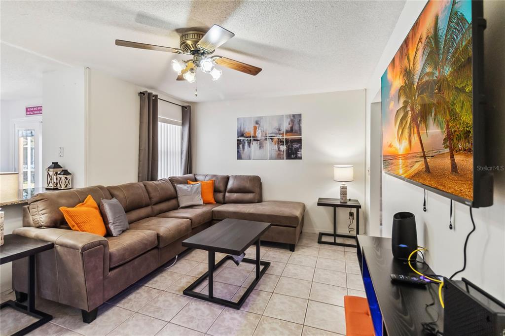 A living room features a brown sectional sofa, a coffee table, and a wall-mounted television — 959 LOMA BONITA DRIVE, DAVENPORT, FL