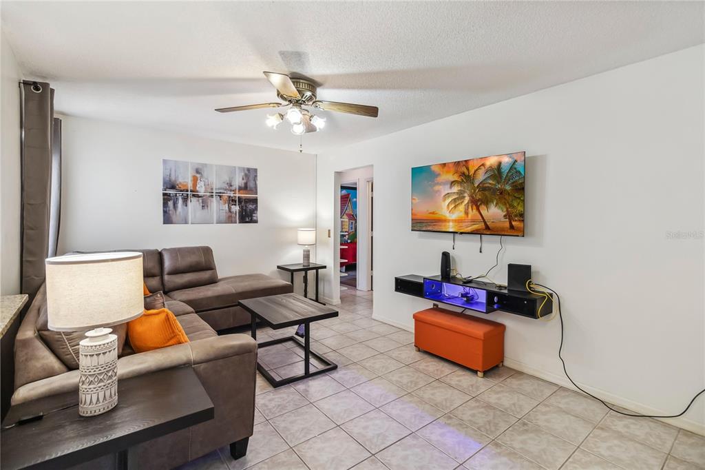 A living room features a brown sectional sofa, a wall-mounted television, and tile flooring — 959 LOMA BONITA DRIVE, DAVENPORT, FL