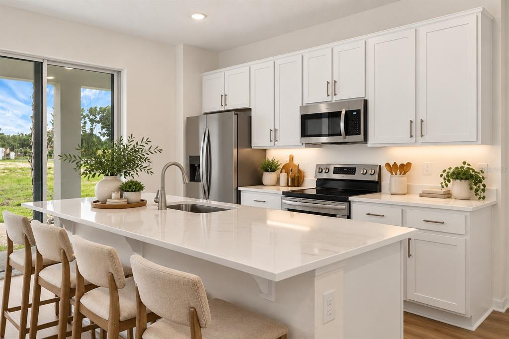 A bright kitchen with white cabinets, a central island, and wood-look flooring — 1156 CYPRESS ELM DRIVE, DELAND, FL