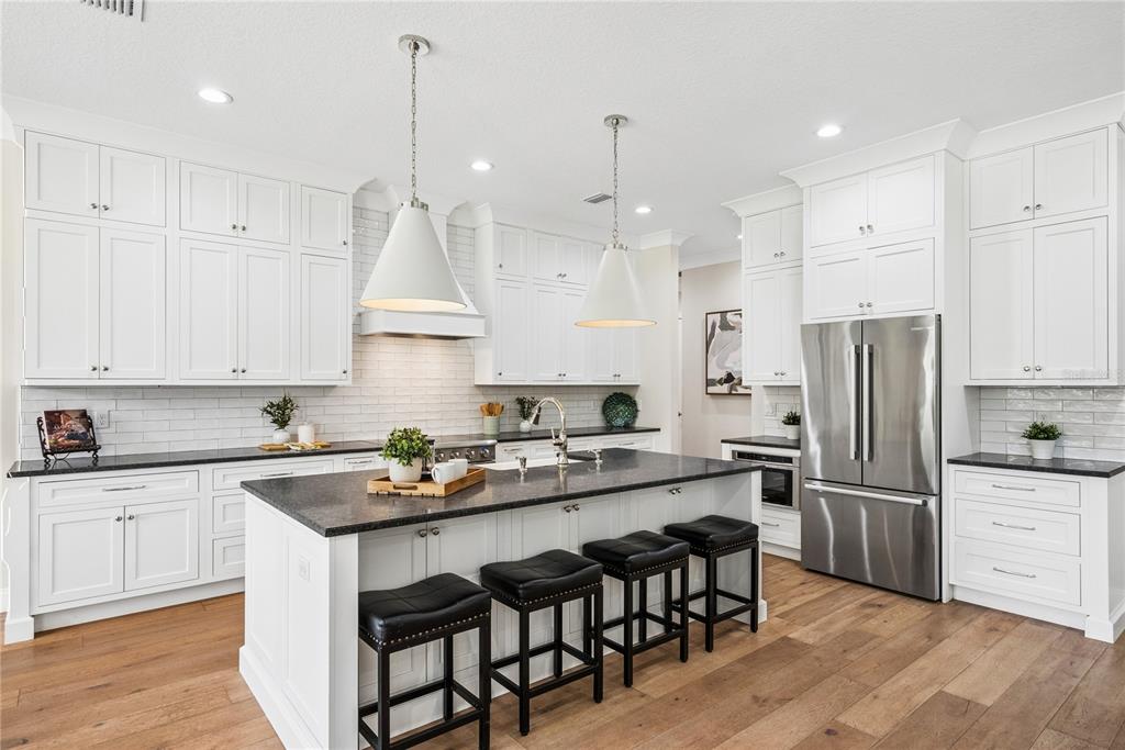 A bright bathroom features white double vanities, marble-look tile flooring, and a large wall mirror — 2370 PINE MEADOWS PLACE, OVIEDO, FL