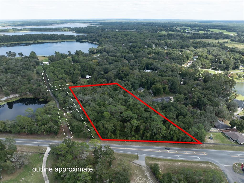 An aerial view shows a wooded, triangular plot of land bordered by a paved road — SR-21, MELROSE, FL