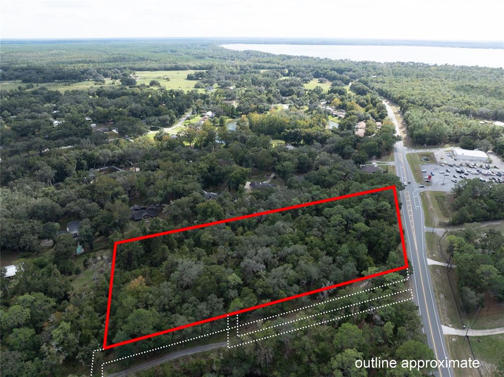 An aerial view shows a wooded, rectangular plot of land outlined in red near a road — SR-21, MELROSE, FL