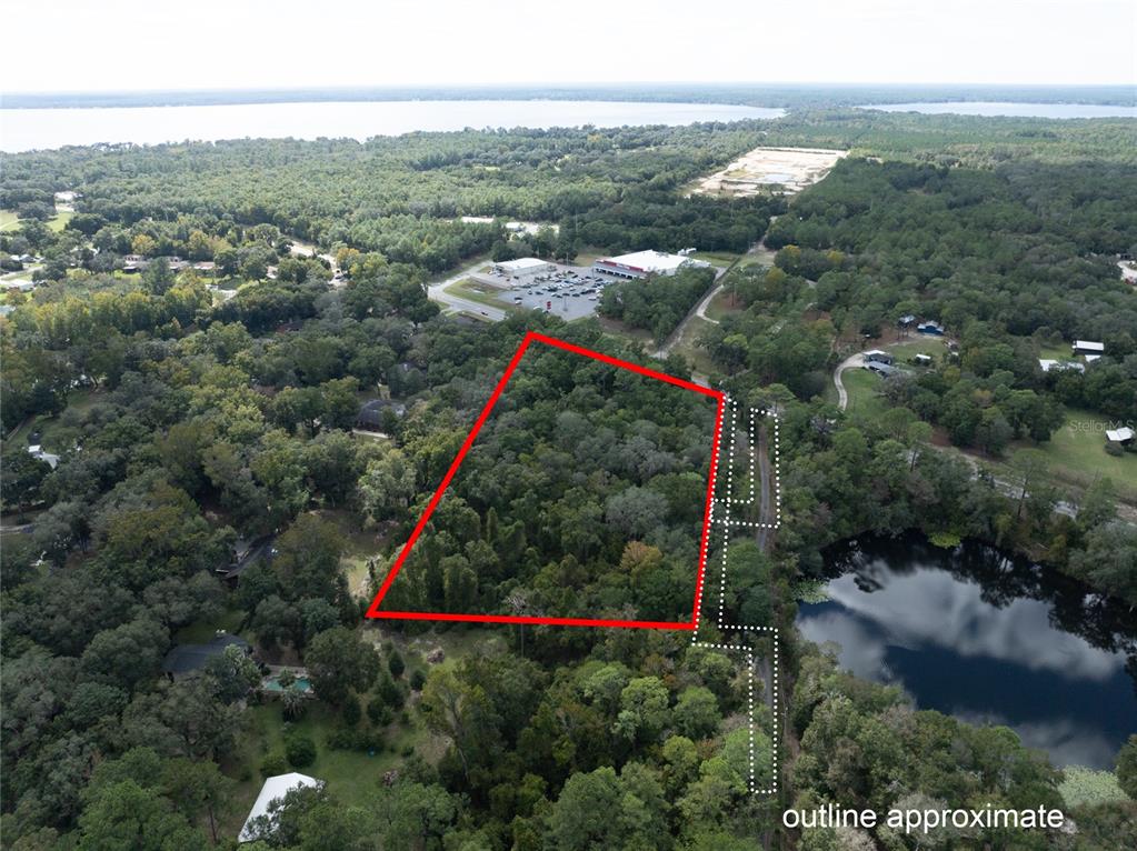 An aerial view shows a wooded plot of land outlined in red near a lake — SR-21, MELROSE, FL