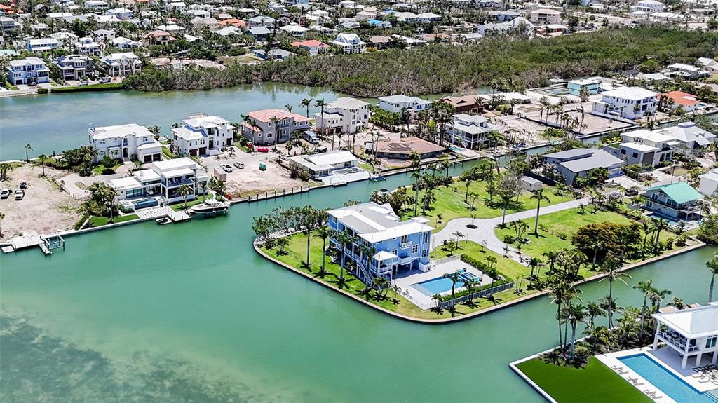 An aerial view shows waterfront homes with swimming pools along a canal in a coastal neighborhood — 630 DE NARVAEZ DRIVE, LONGBOAT KEY, FL