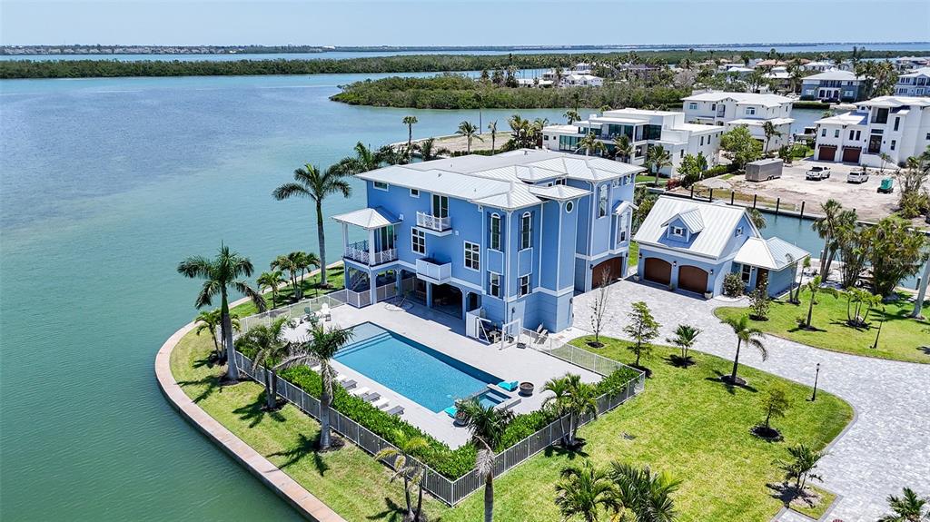 An aerial view shows a blue three-story house with a pool and detached garage — 630 DE NARVAEZ DRIVE, LONGBOAT KEY, FL