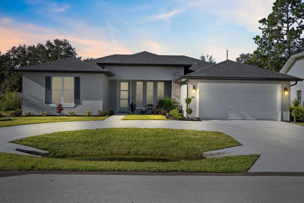 A single-story house with a gray exterior, a two-car garage, and a circular concrete driveway — 94 FOREST HILL DRIVE, PALM COAST, FL