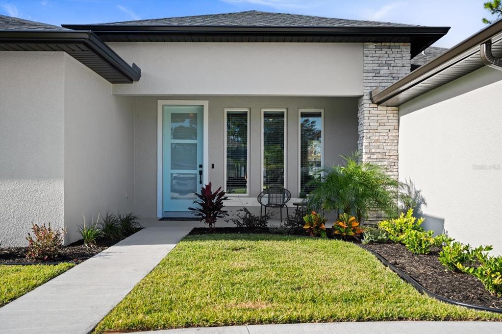 The exterior of a house features a light blue front door, stone accents, and landscaping — 94 FOREST HILL DRIVE, PALM COAST, FL