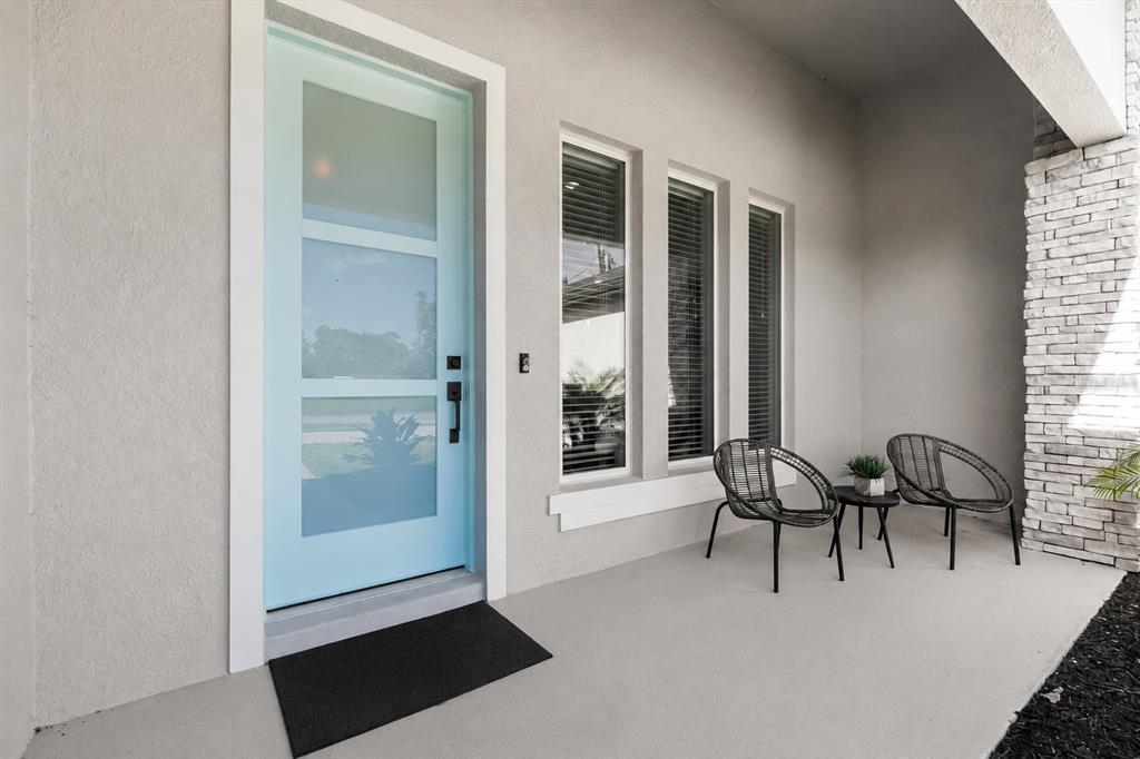 A light blue front door sits next to two chairs on a concrete porch — 94 FOREST HILL DRIVE, PALM COAST, FL