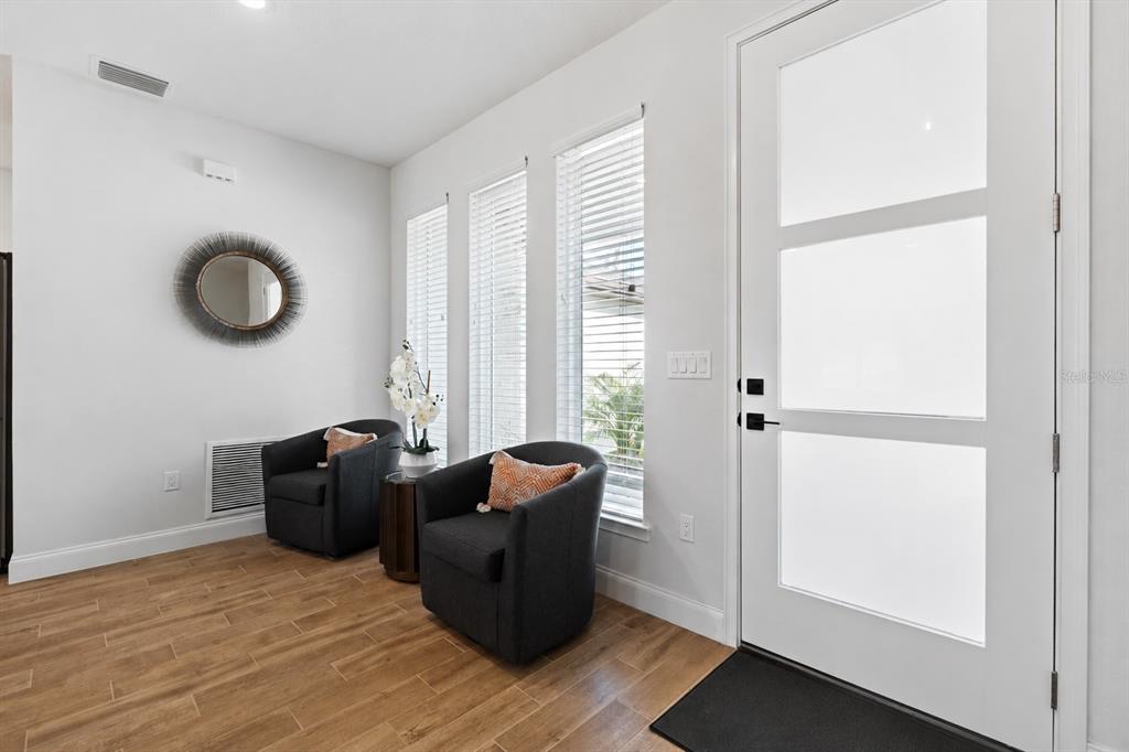 An entryway features two dark armchairs, a round mirror, and a white front door — 94 FOREST HILL DRIVE, PALM COAST, FL