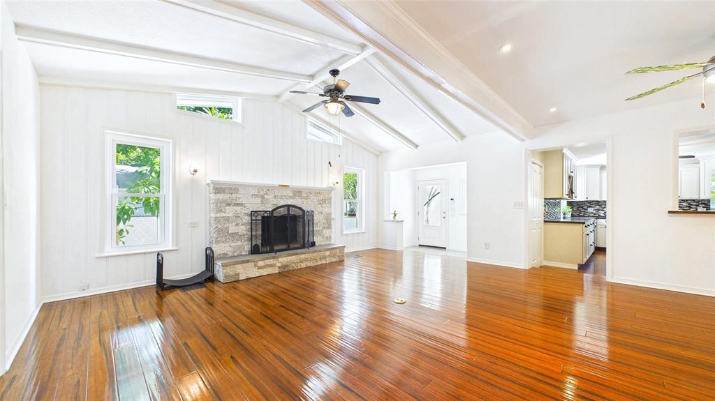 A living room features a stone fireplace, vaulted ceiling, wood flooring, and a massage chair — 5005 24TH AVENUE S, GULFPORT, FL
