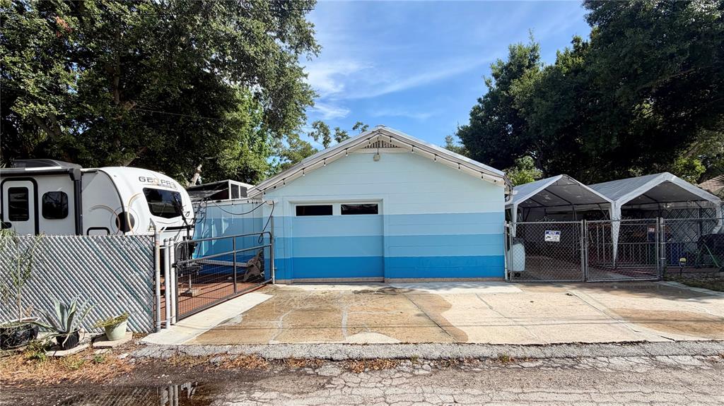 A light blue house with a metal roof sits next to a fenced-in carport area — 5005 24TH AVENUE S, GULFPORT, FL