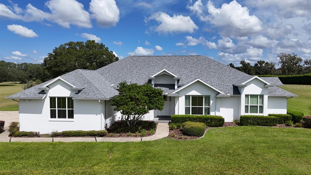 A white single-story house with a gray shingled roof sits on a grassy lawn — 601 SE 80TH STREET, OCALA, FL