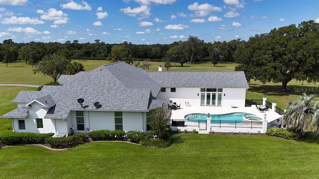 An aerial view of a white house with a gray shingled roof and backyard pool — 601 SE 80TH STREET, OCALA, FL