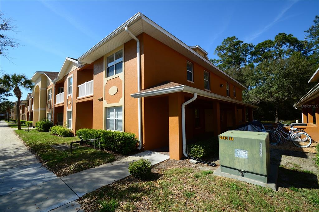 A two-story orange apartment building with a sidewalk and a utility box in the foreground — 4600 E MOODY BOULEVARD UNIT 8D, BUNNELL, FL