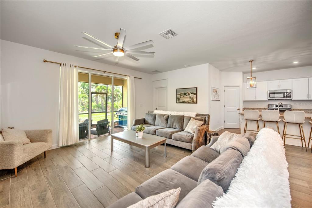 A living room with gray tile floors, a large sectional sofa, and a sliding glass door — 3254 WESTON MANOR DRIVE, ALVA, FL