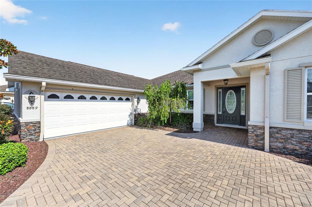 A single-story house with a paved driveway, stone accents, and landscaped front yard — 8889 SW 86TH LOOP, OCALA, FL