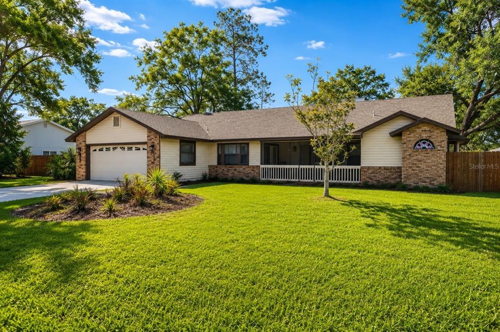 A single-story house with a two-car garage, brick accents, and a screened-in front porch — 9502 59TH AVENUE E, BRADENTON, FL