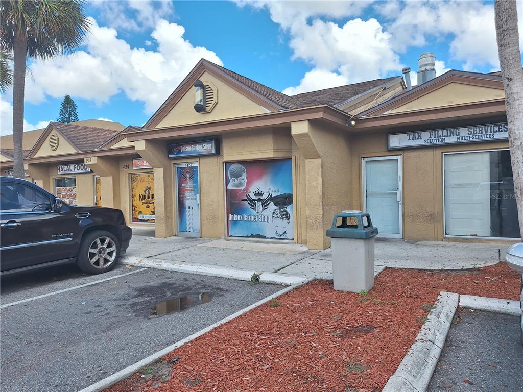 A strip mall exterior features a barber shop and a tax service office under a roof — 1402 E FLETCHER AVENUE UNIT 1426, TAMPA, FL