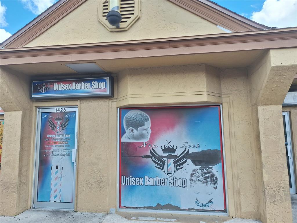 The exterior of a tan commercial building features a storefront with a unisex barber shop sign — 1402 E FLETCHER AVENUE UNIT 1426, TAMPA, FL