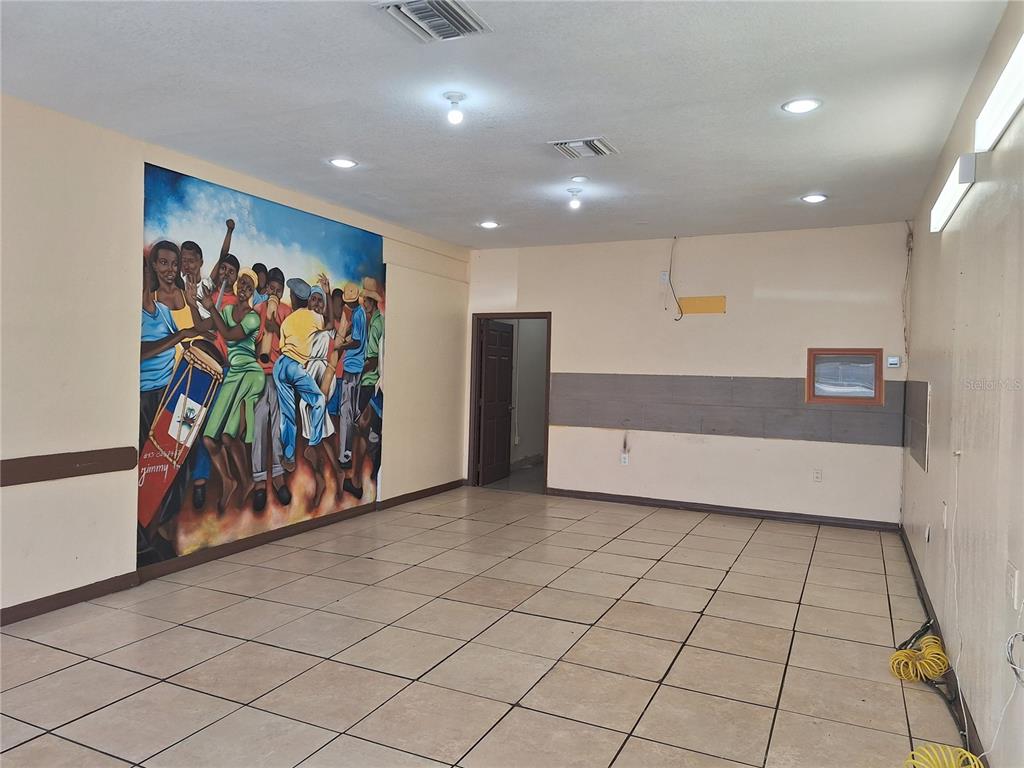 An empty commercial space features a large mural on one wall and tiled flooring — 1402 E FLETCHER AVENUE UNIT 1426, TAMPA, FL