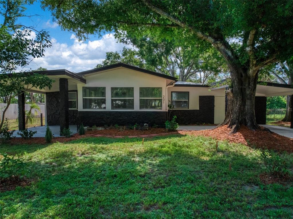 A single-story house with a carport, dark stone accents, and large trees in the yard — 201 BROOKS ROAD, FROSTPROOF, FL