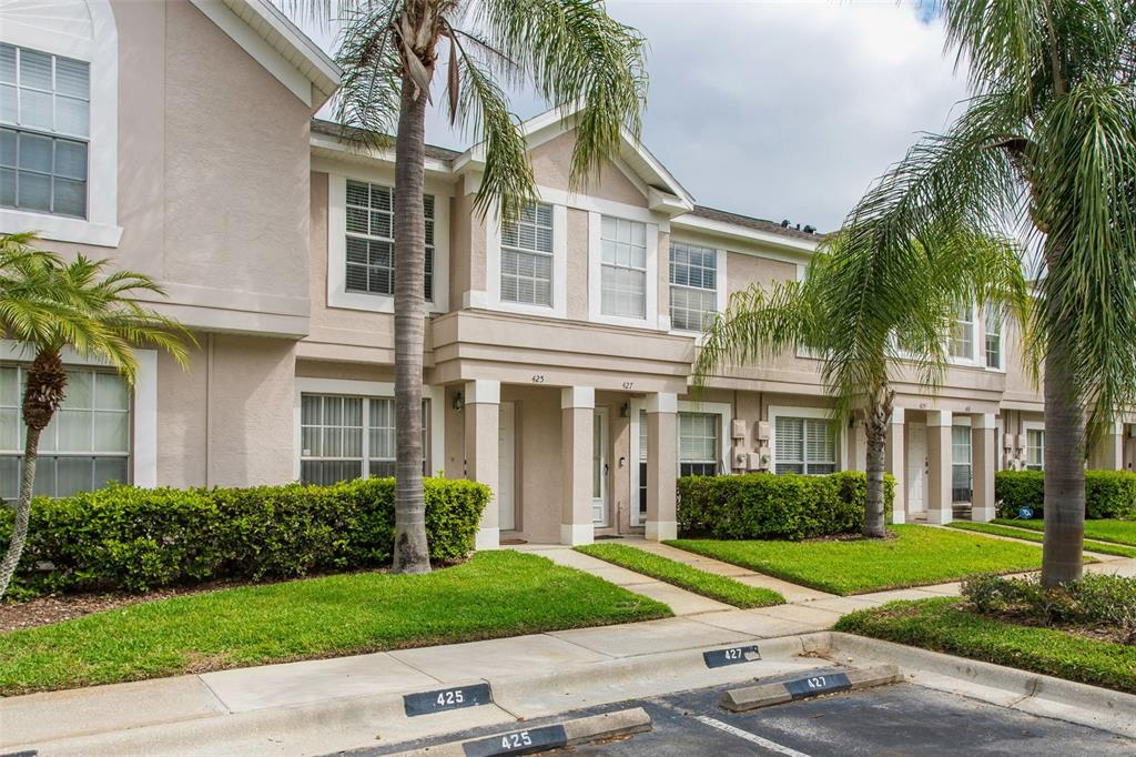 A two-story tan townhouse exterior features palm trees, a sidewalk, and numbered parking spaces — 425 KENSINGTON LAKE CIRCLE, BRANDON, FL