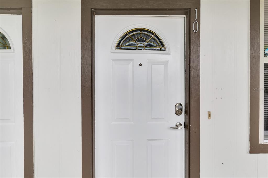 A white front door with a decorative glass arch window and a digital keypad lock — 6519 W NEWBERRY ROAD UNIT A10, GAINESVILLE, FL