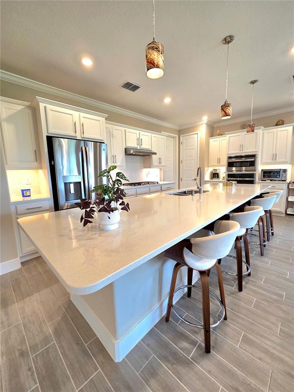 A modern kitchen features white cabinetry, a large quartz island, and three bar stools — 4215 NW 55TH TERRACE, OCALA, FL