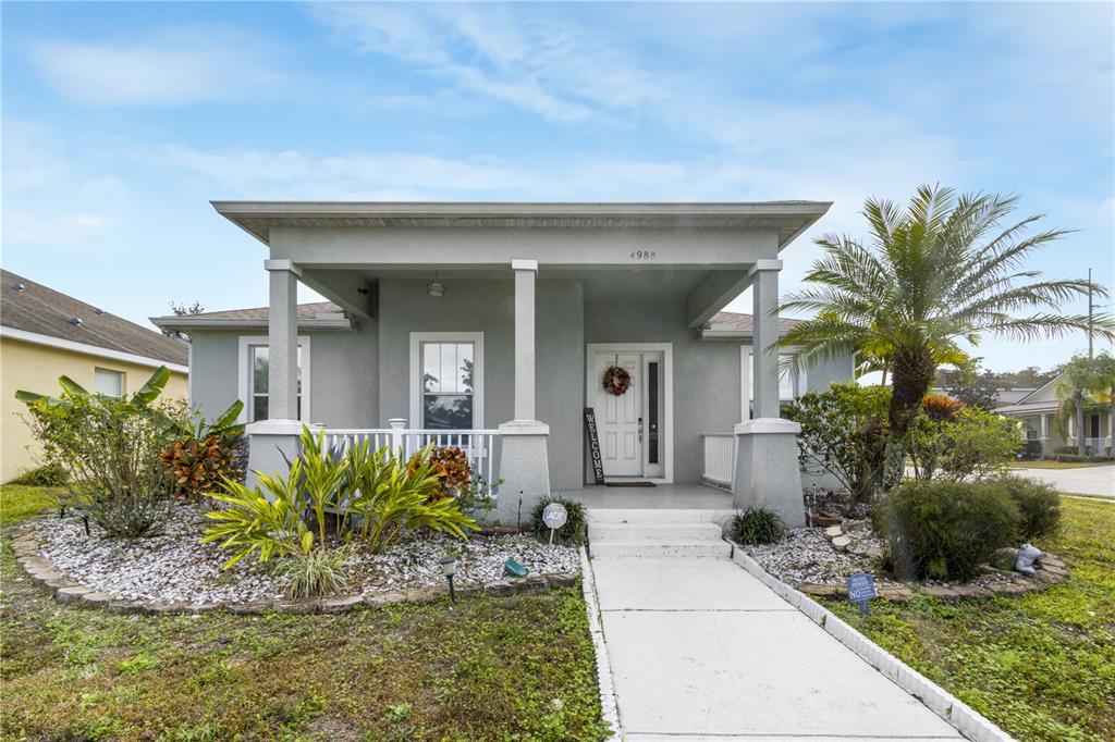 A gray single-story house features a covered front porch, white columns, and a concrete walkway — 4988 BOND STREET W, KISSIMMEE, FL