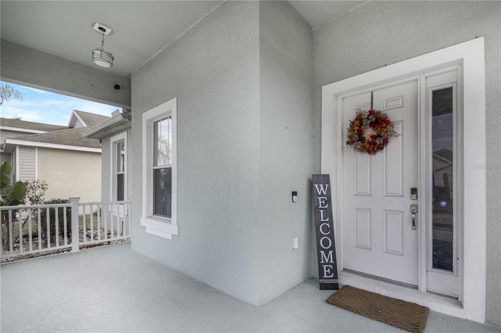 A covered front porch features a white door with a wreath and a welcome sign — 4988 BOND STREET W, KISSIMMEE, FL