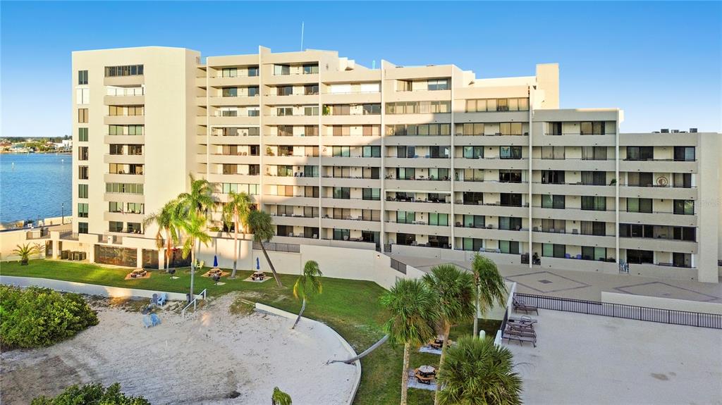 An exterior view of a multi-story apartment building with a beach area and palm trees — 6035 SEA RANCH DRIVE UNIT 415, HUDSON, FL