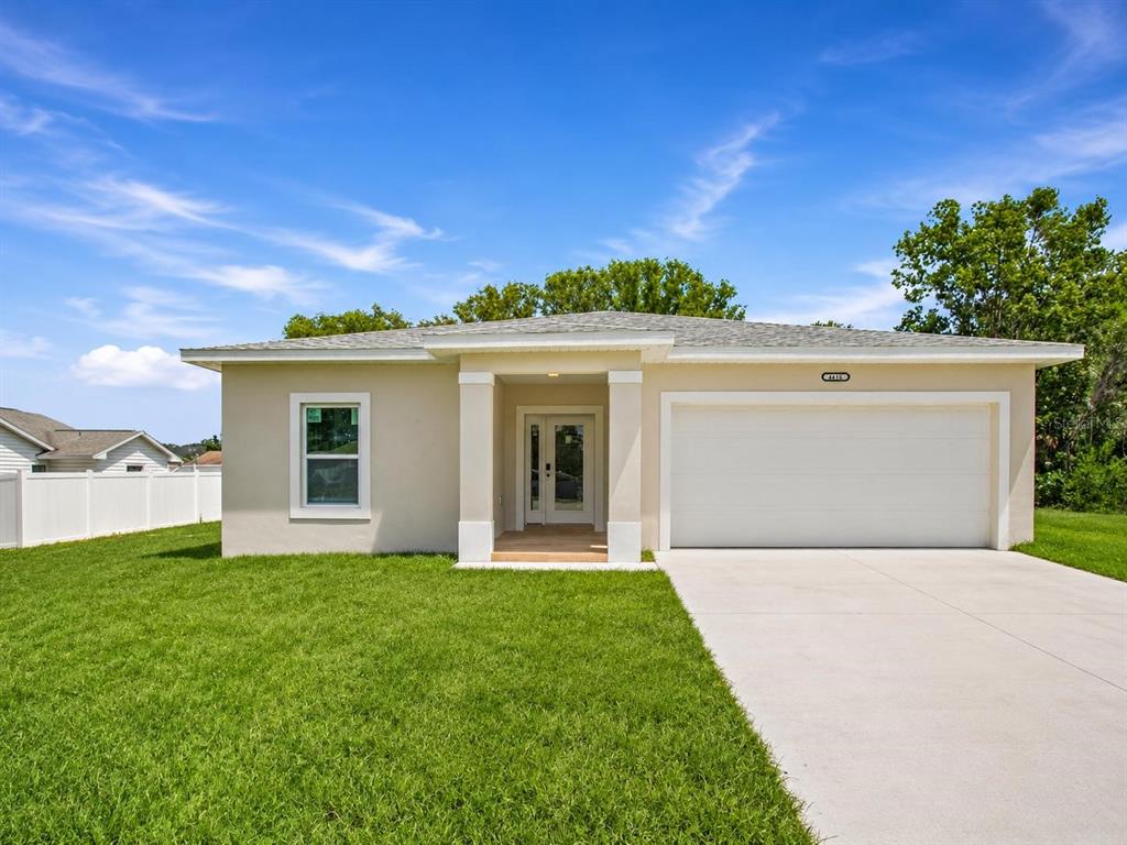 A single-story house with a beige exterior, a white garage door, and a front porch — 4416 MARINER BOULEVARD, SPRING HILL, FL
