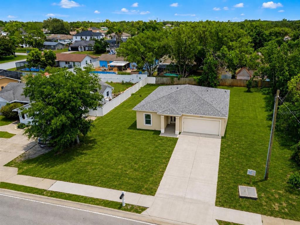 An aerial view shows a single-story house with a gray roof and a concrete driveway — 4416 MARINER BOULEVARD, SPRING HILL, FL