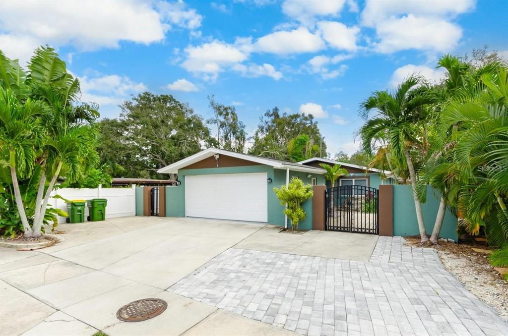 A teal house with a white garage door, a paved driveway, and surrounding palm trees — 2598 WOOD STREET, SARASOTA, FL