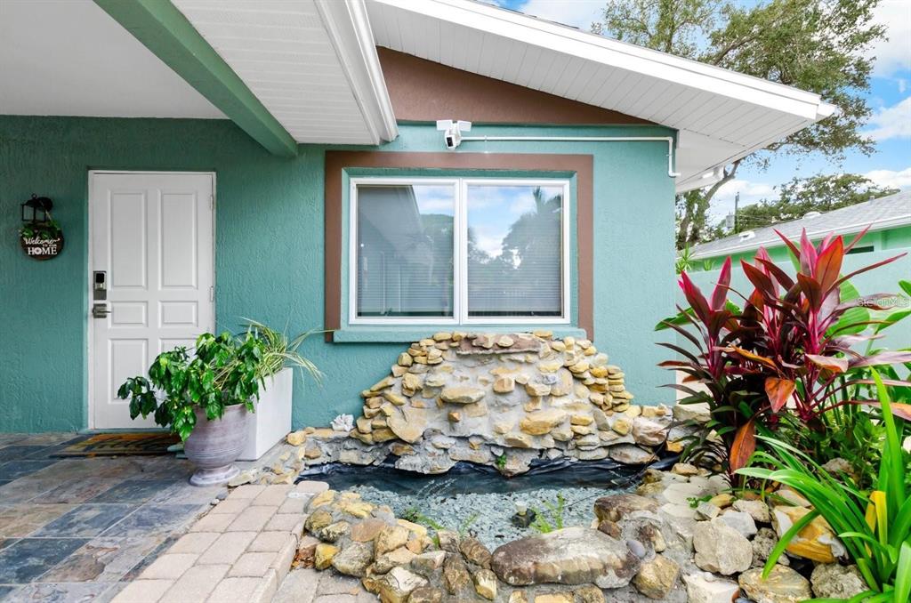 A teal house exterior features a front door, a window, and a stone water feature — 2598 WOOD STREET, SARASOTA, FL