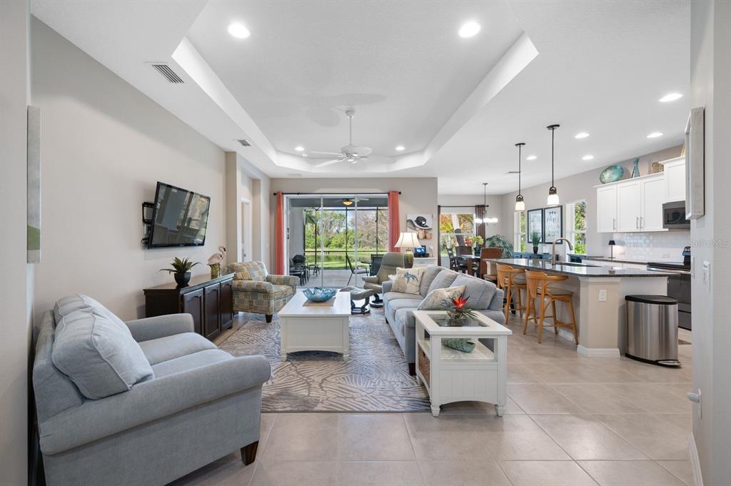 An open-concept living room and kitchen with a tray ceiling, tile floors, and sliding doors — 1549 WESTOVER AVENUE, PARRISH, FL
