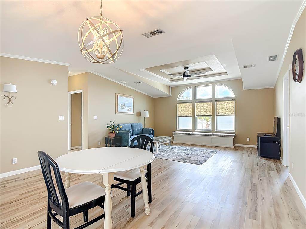 A living room and dining area with light wood flooring, a chandelier, and arched windows — 452 PAR DRIVE, FROSTPROOF, FL