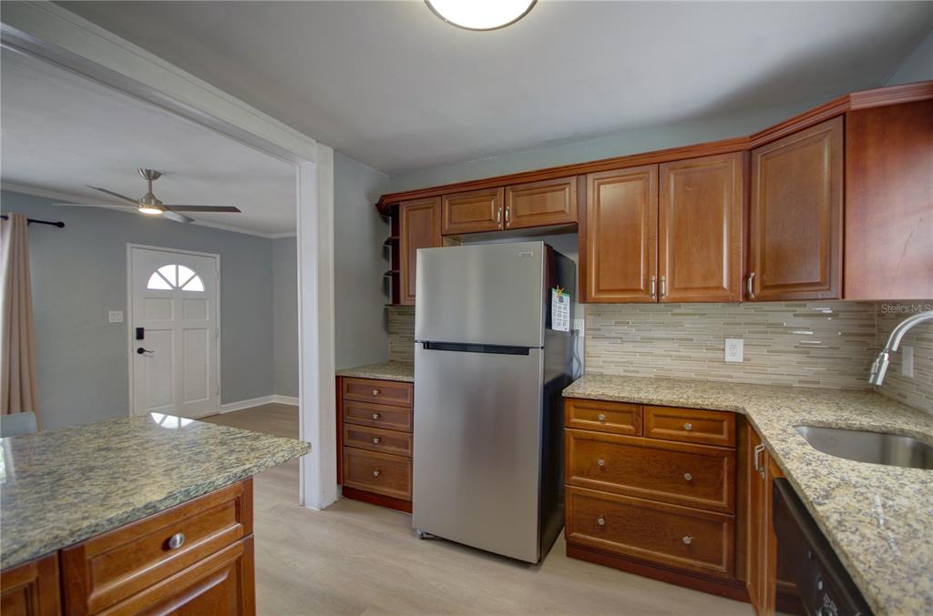 A kitchen features wood cabinets, granite countertops, a stainless steel refrigerator, and light flooring — 820 86TH AVENUE N, ST PETERSBURG, FL