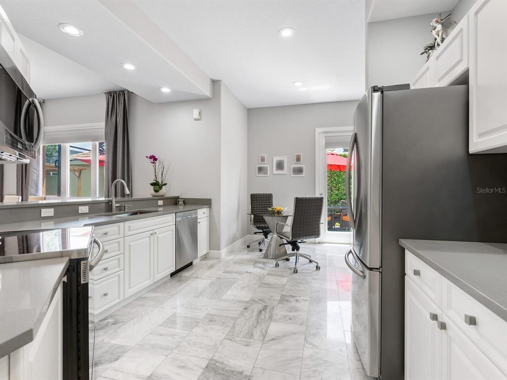 A kitchen with white cabinets, gray countertops, stainless steel appliances, and marble-look tile flooring — 5237 97TH STREET E, BRADENTON, FL