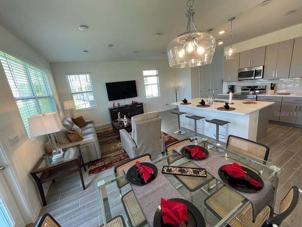 An open-concept living and dining area features a kitchen island, gray cabinetry, and tile flooring — 935 CONCH ROAD, DAVENPORT, FL