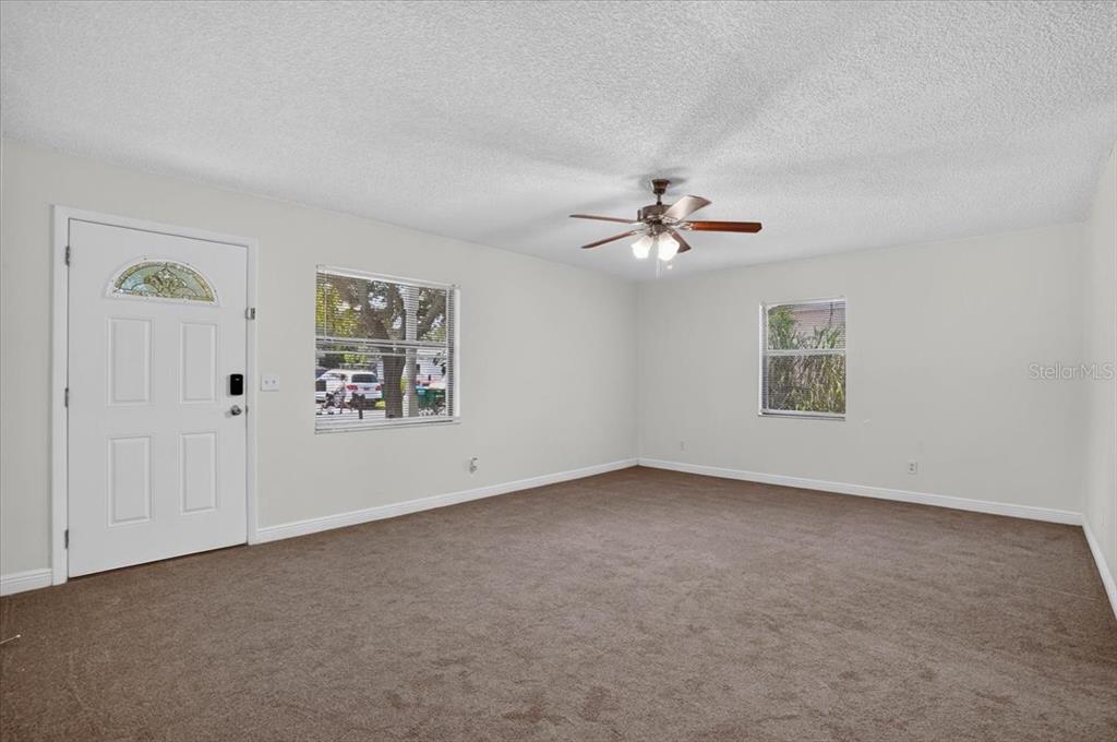An empty living room features brown carpet, white walls, two windows, and a ceiling fan — 12641 116TH LANE, SEMINOLE, FL