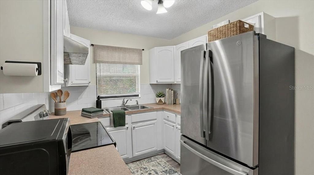 A kitchen features white cabinets, stainless steel appliances, a window, and light-colored countertops — 12641 116TH LANE, SEMINOLE, FL
